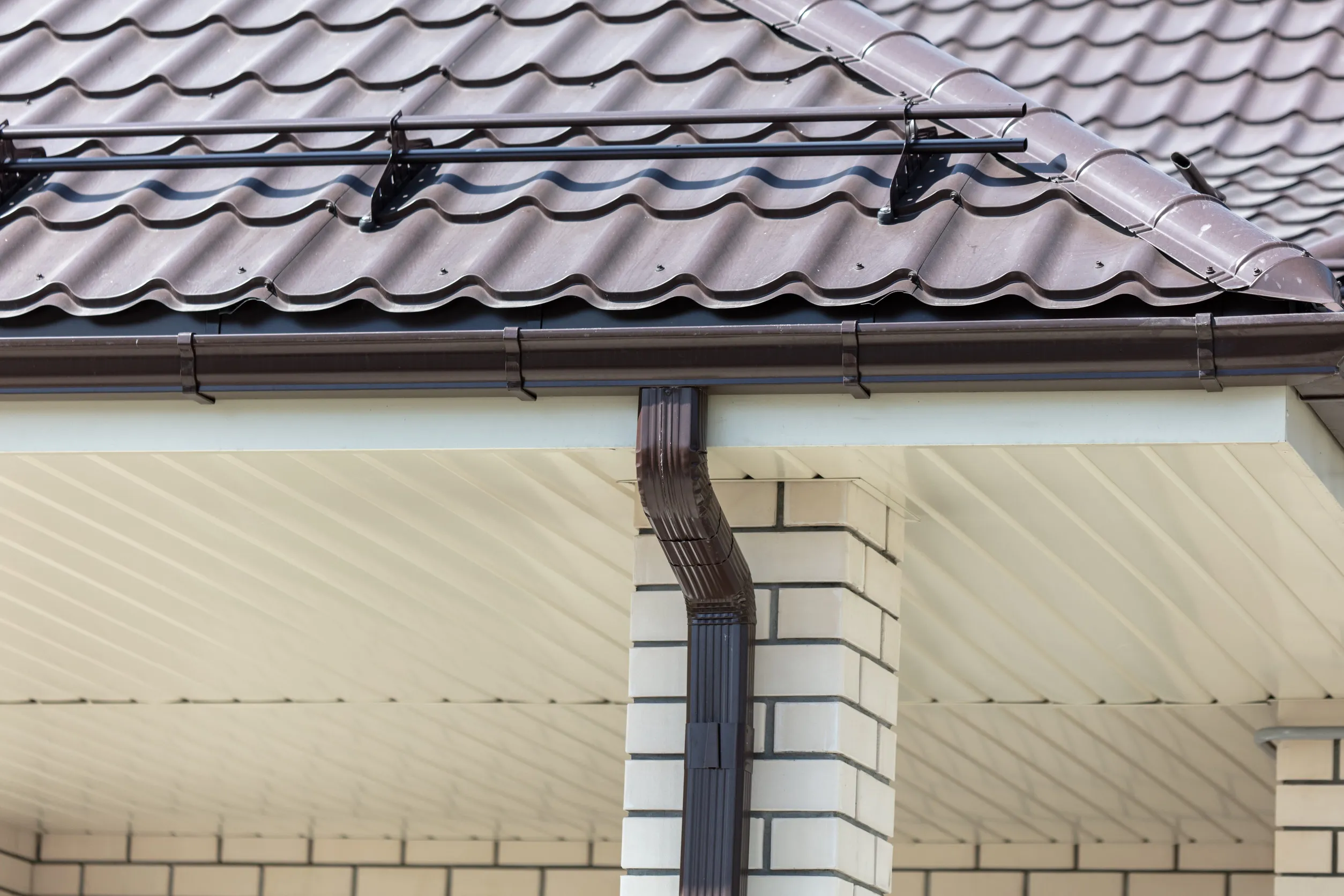 Brown metal gutter on the roof of the house